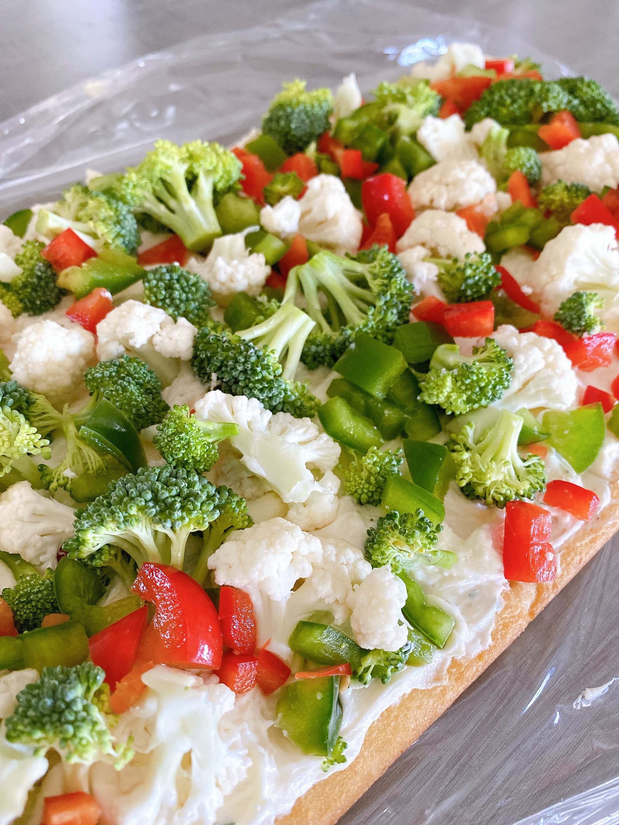 close up of easy cold veggie pizza topped with green broccoli and peppers, white cauliflower, and red bell peppers.