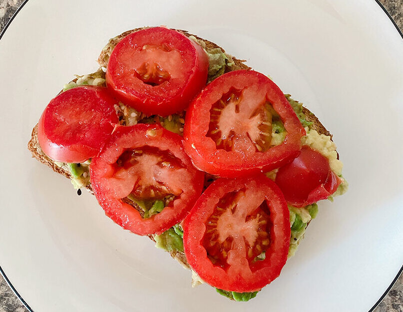 Easy avocado toast with tomatos and seasoning on a plate.