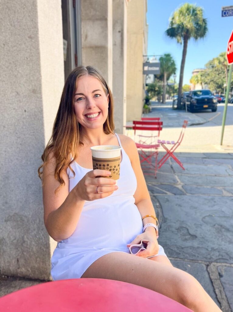 pregnant woman sitting outside a coffee shop drinking coffee