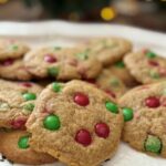 close up shot of festive christmas m&m cookies with tree lights in the background