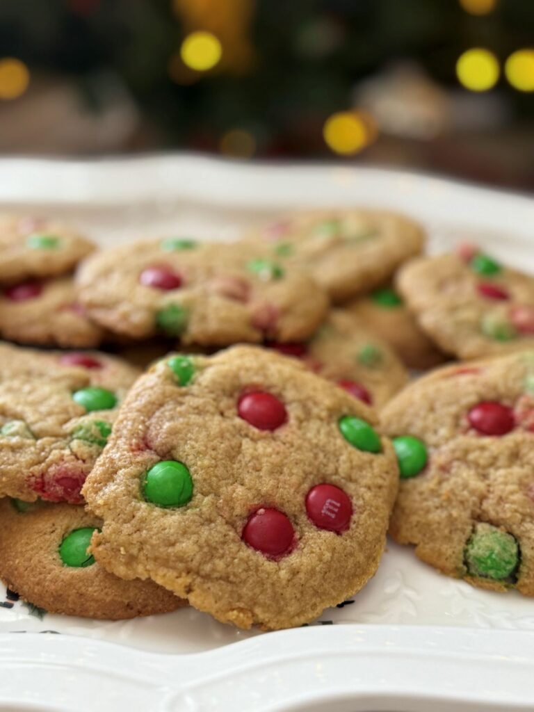 close up shot of festive christmas m&m cookies with tree lights in the background