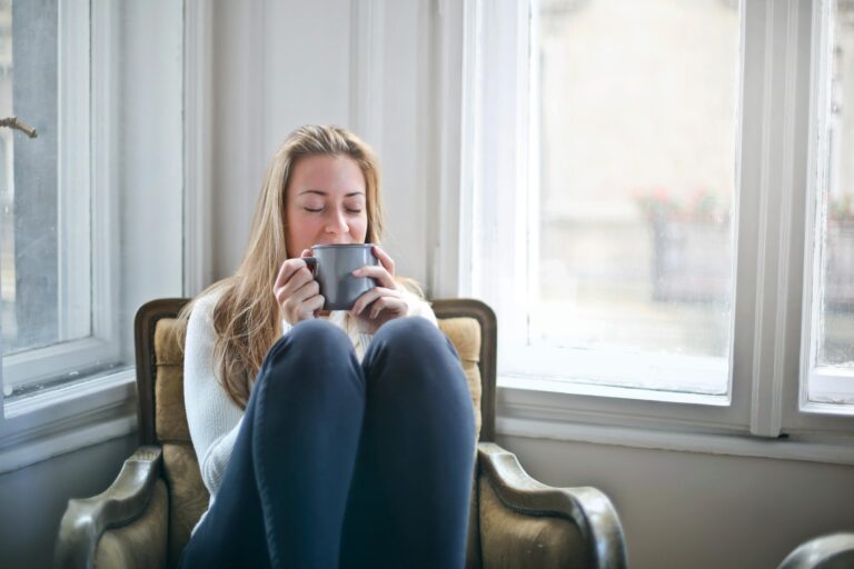 A woman sitting quietly by a window with a cup of coffee, reflecting — a visual metaphor for why stress feels worse in your 40s.