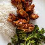 a plate of juicy cooked honey garlic chicken with roasted broccoli and rice