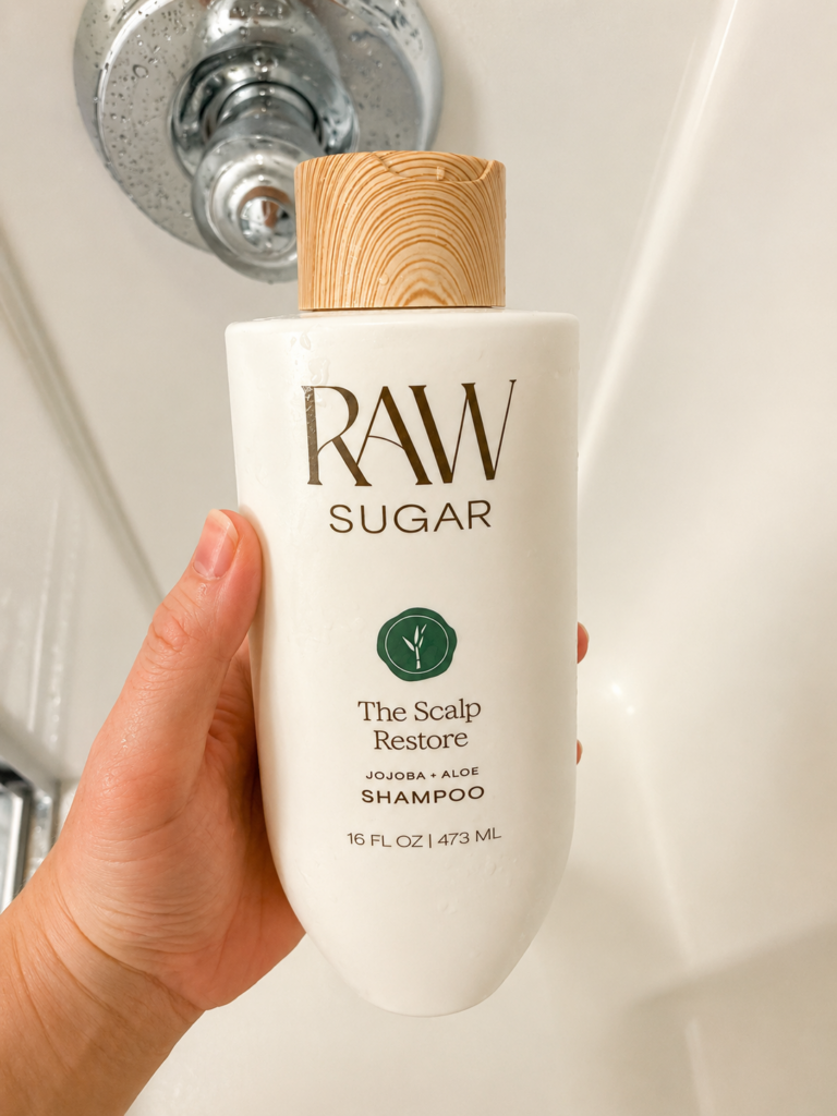 Raw Sugar The Scalp Restore shampoo bottle held in the shower during a real-life product review