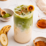Iced banana bread matcha latte with creamy banana milk, matcha, cinnamon, and banana garnish in a clear glass.