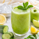 refreshing glass of fresh cucumber mint juice with mint garnish surrounded by recipe ingredients