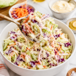 Easy coleslaw recipe with creamy homemade dressing tossed with cabbage, carrots, and purple cabbage in a white bowl.