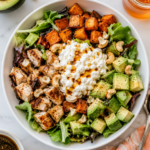Hot honey cottage cheese bowl with chicken, roasted sweet potatoes, avocado, mixed greens, cashews, balsamic vinaigrette, and hot honey.