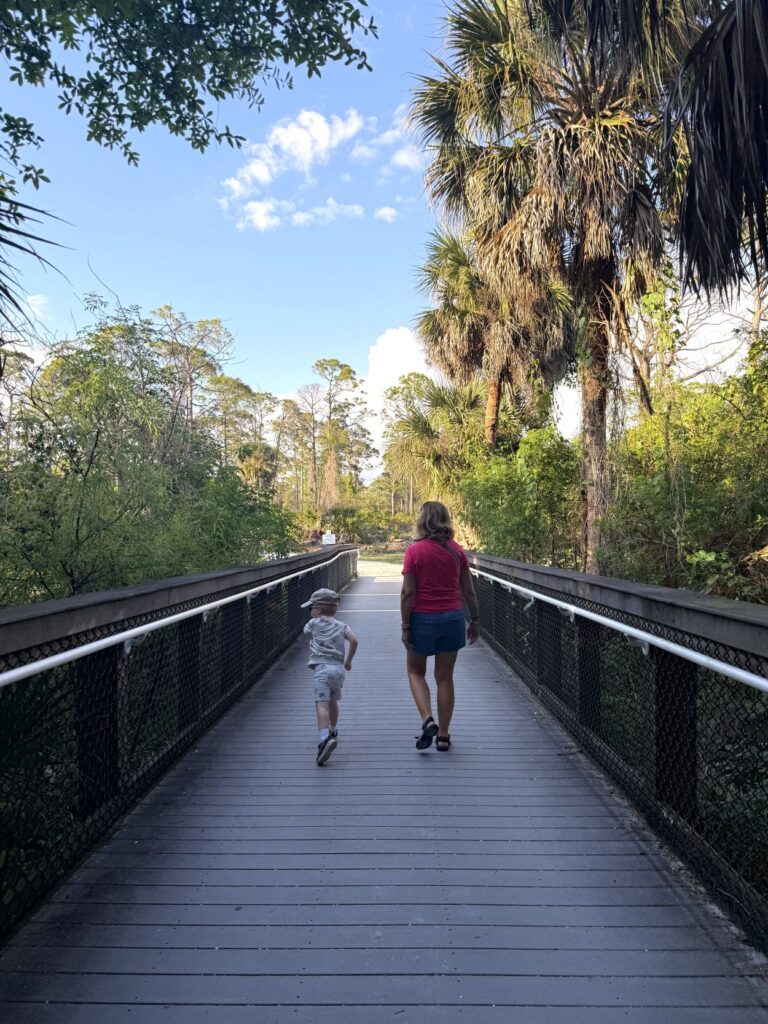 Grandmother and toddler walking over bridge through Indian Mound Park in Englewood Florida