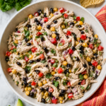 Mexican chicken salad with cottage cheese dressing, black beans, corn, red bell pepper, and cilantro in a white bowl with avocado and tortilla chips.