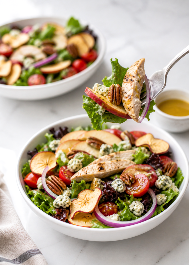 two bowls of apple chicken salad with bit on a fork