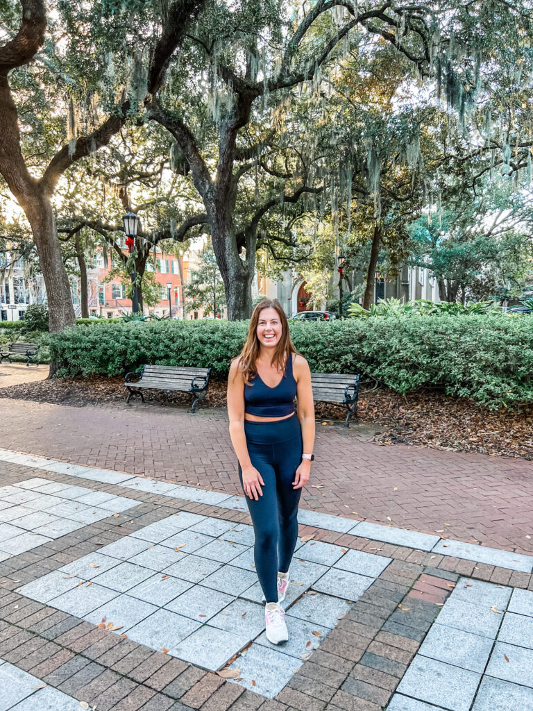 Woman wearing a dark Athleta matching set with leggings and a crop top while traveling.