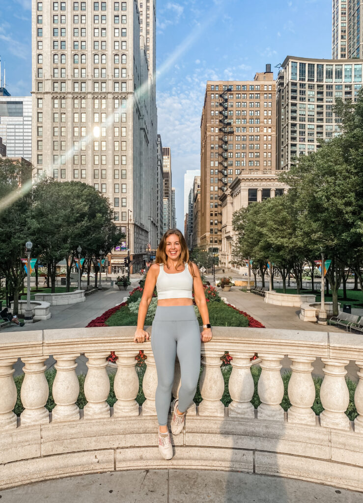 Woman wearing a green-ish gray Athleta leggings and white Athleta crop top outfit while exploring the city.