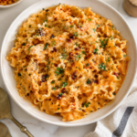 Creamy chili oil pasta with mafaldine noodles, chili crisp, parmesan, black pepper, and parsley in a white bowl.