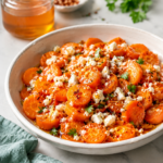 Hot honey feta carrots made with sliced canned carrots, crumbled feta, parsley, red pepper flakes, and a glossy hot honey glaze in a white ceramic bowl.