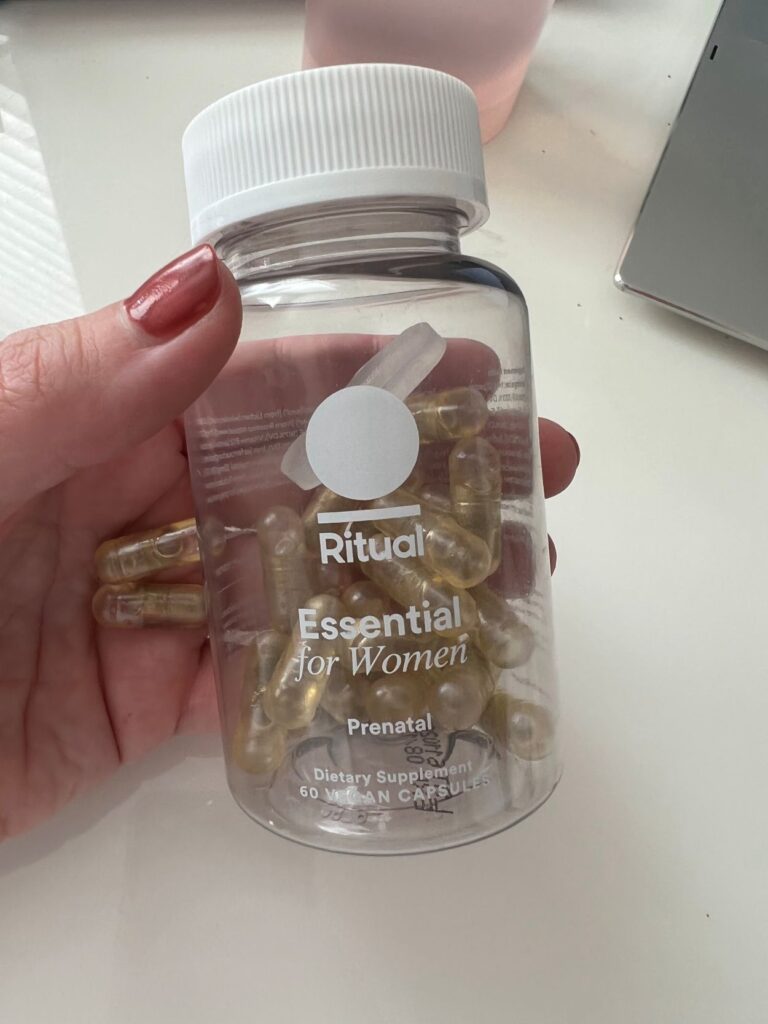 hand holding bottle of Ritual Essential Prenatal bottle of vitamins at work desk