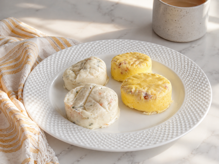 Cooked Costco egg bites on a white plate with coffee after heating in the microwave