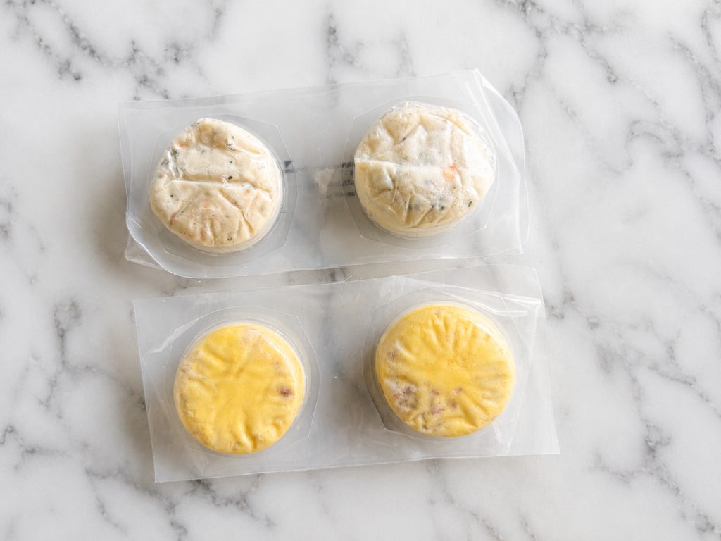two vacuum-sealed packages of frozen Costco sous vide egg bites on marble countertop.